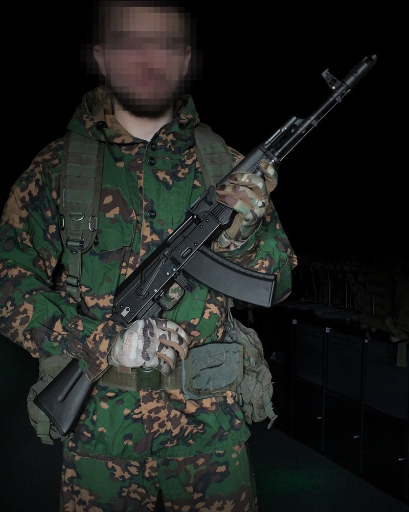 Person in camouflage gear holding a VFC AV74 GBBR Airsoft Rifle against a dark background