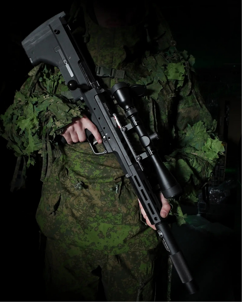 Person in camouflage holding a Silverback SRS Airsoft Sniper Rifle against a dark background